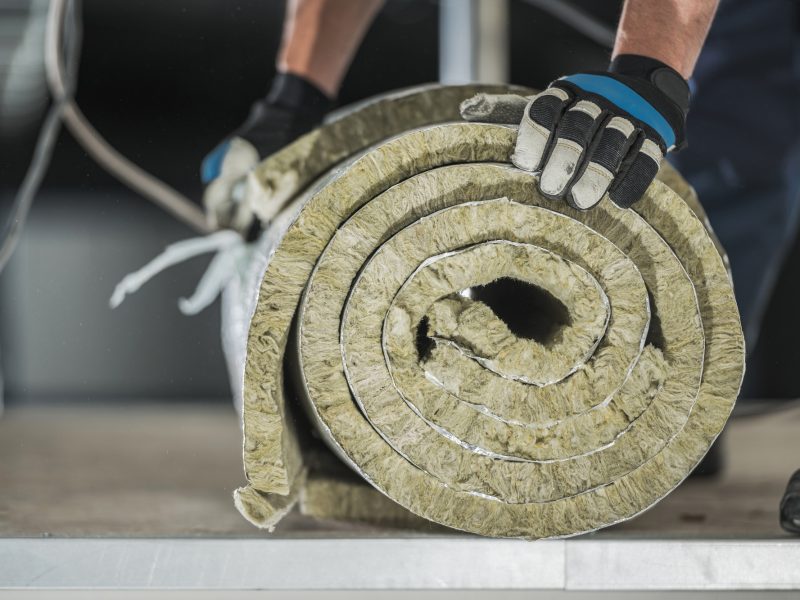 Construction Worker Preparing Roll of Mineral Wool Insulation