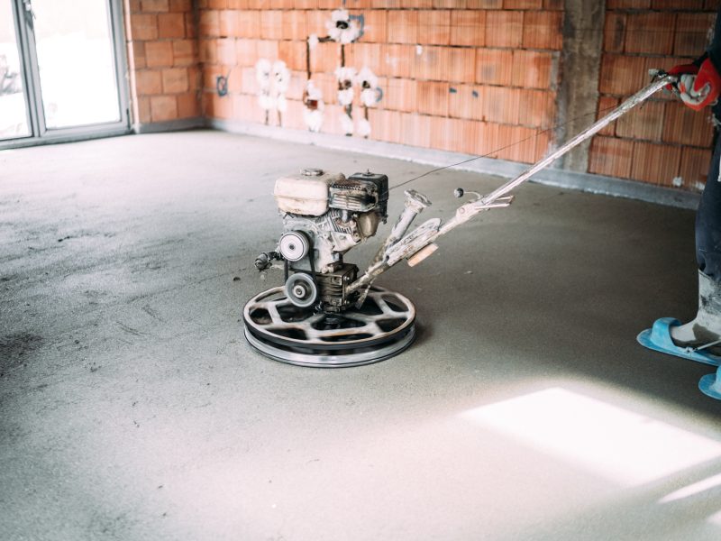 industrial worker finishes concrete screed with trowel machine