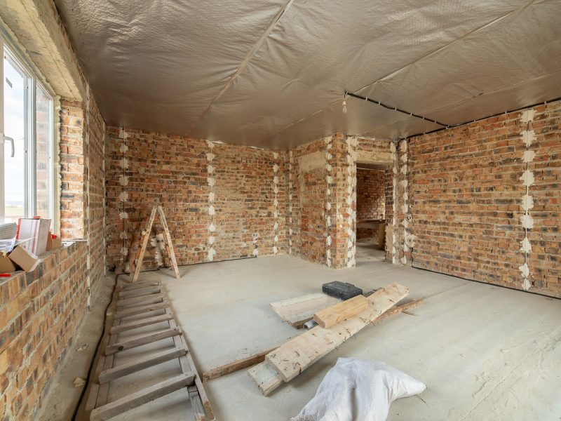 Interior of unfinished brick house with concrete floor and bare walls ready for plastering