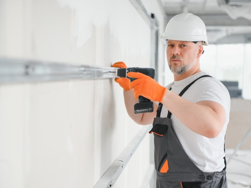 man drywall worker installing plasterboard sheet to wall