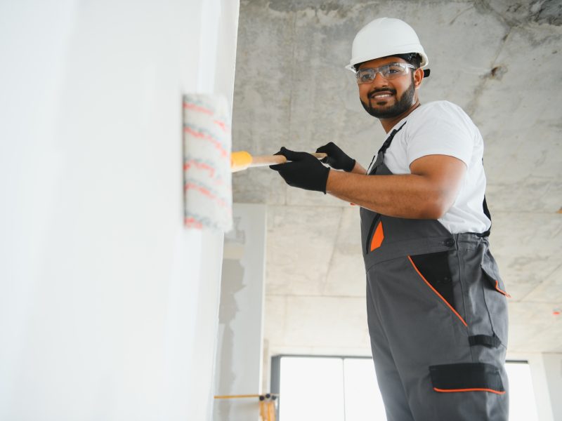 painter doing painting work on wall with roller. concept of hard working, home renovation